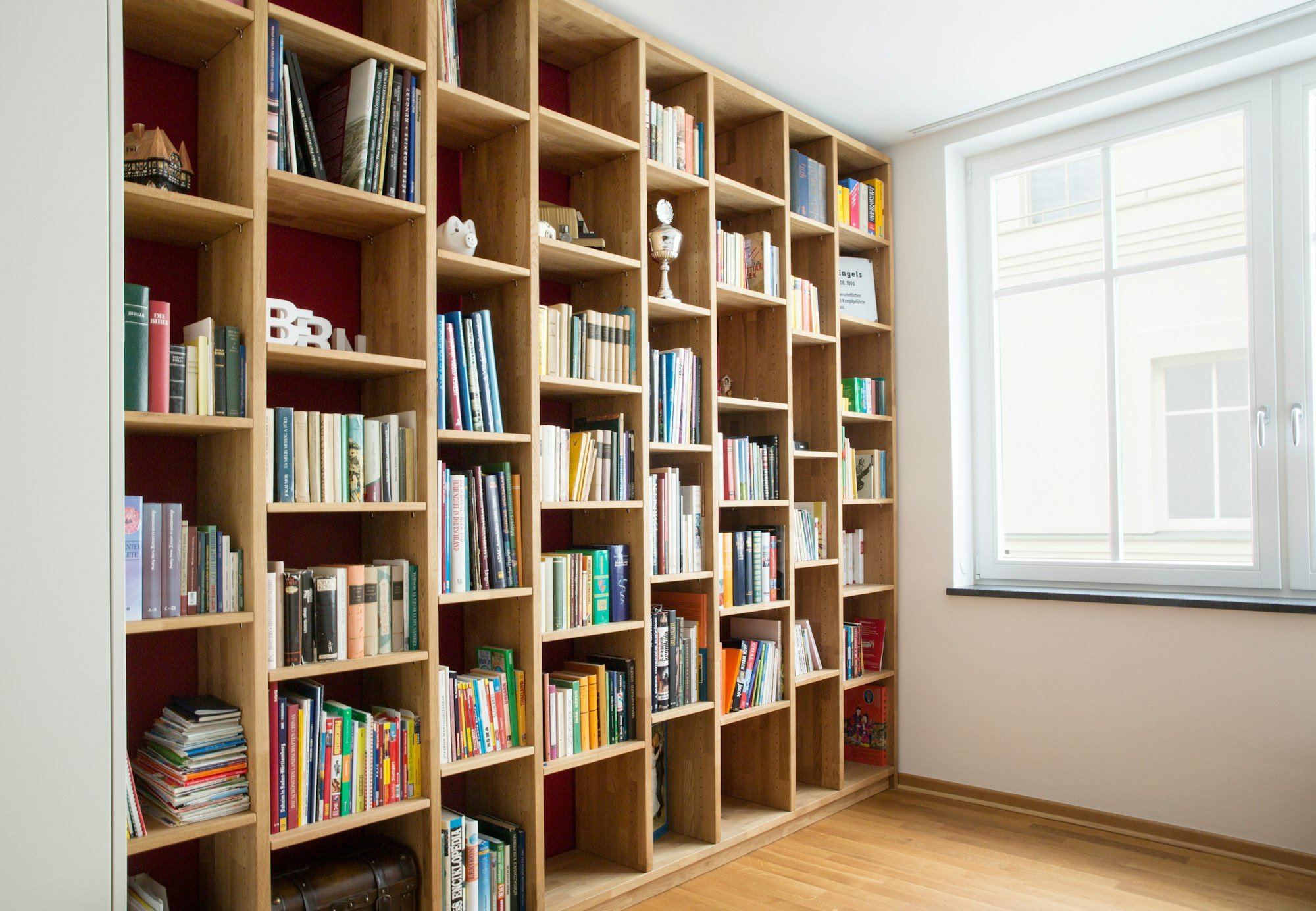 Une bibliothèque en chêne du sol au plafond, à côté d’une fenêtre